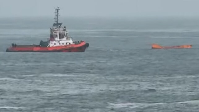 container floating in ocean with tugboat 