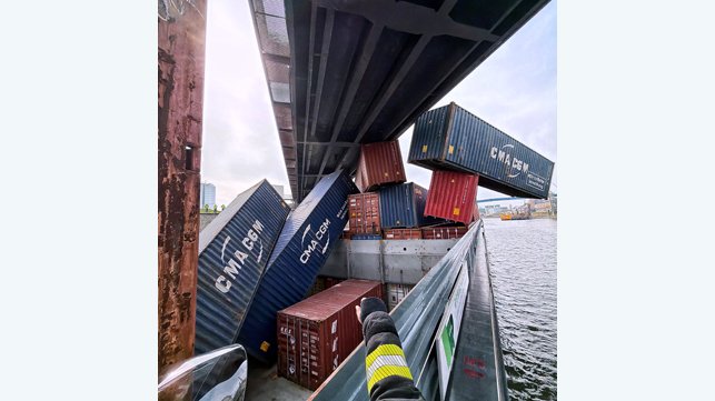 containers dangling from cargo ship stuck under railway bridge