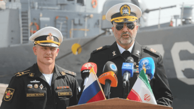 Rear Admiral Hassan Maqsoudlou gives a dockside welcome to Captain Sergeev in front of the Jamaran (FarsNews)